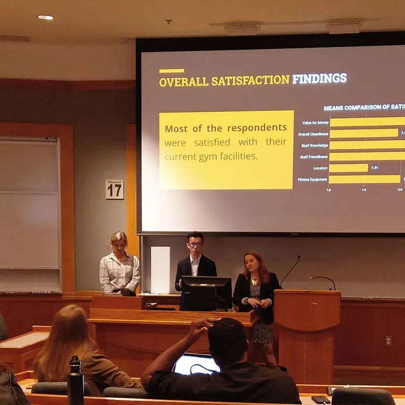John presenting customer satisfaction survey findings to a lecture hall